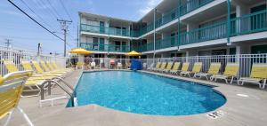 大洋城Shangri-La Motel的酒店前的游泳池设有黄色椅子