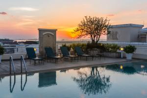 是拉差Classic Kameo Hotel and Serviced Apartments, Sriracha的一个带椅子的游泳池,享有日落美景