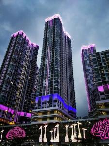 莎阿南I City Residence, 2 Bedroom 4-6 Pax unit, Walking to Theme n Water Park & Shopping Mall的三幢高楼,上面有紫色的灯