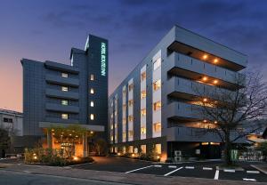 千曲市HOTEL ROUTE-INN Kamiyamada Onsen的一座高大的建筑,前面有一个停车位