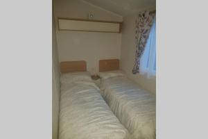 布莱克浦Stunning deluxe 3 bedroomed caravan with CH, DG and decking.的一间位于角落的卧室,配有两张床