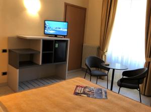 维亚雷焦蒂雷尼亚酒店的配有电视和桌椅的房间