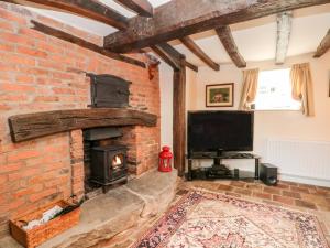 塔博雷Chapel Cottage的客厅设有砖砌壁炉和电视。