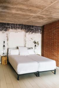 巴塞罗那巴塞罗那共和公寓酒店的砖墙房间内的一张白色床