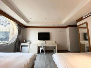 高雄The Rivero Hotel的酒店客房设有两张床、一张书桌和电视