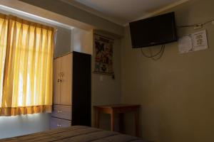 阿亚库乔Hostal Roma的卧室配有一张床,墙上配有电视