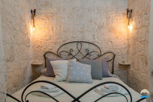 奥斯图尼Casa Francesca的一间卧室配有带枕头的床铺和石墙