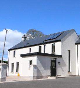 莫纳汉Emy Lake Apartment - near Castle Leslie, Glaslough的屋顶上设有太阳能电池板的白色房子