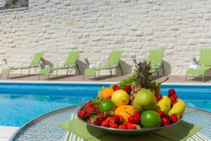 赫瓦尔Villa Kogo的游泳池畔的桌子上放上一碗水果