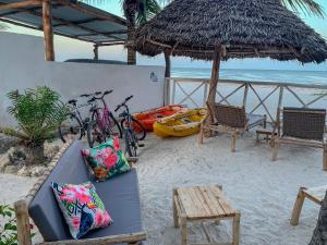 布韦朱The African Paradise Beach Hotel的海滩上的一张沙发和两辆自行车