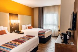 克萨尔特南戈LATAM HOTEL Plaza Pradera Quetzaltenango的酒店客房设有两张床和电视。