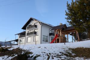 瓦特拉多尔内PENSIUNEA ARINAS的雪中带红色滑梯的白色房子