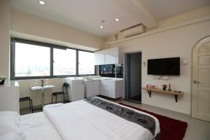 新加坡JJH Serviced Apartments near Serangoon MRT的卧室配有白色的床和平面电视。