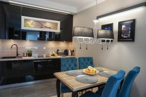 克拉科夫AGA Tenis Apartments by Radwańska的厨房以及带桌子和蓝色椅子的用餐室。