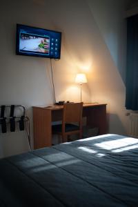 泽尔扎特JFK Hotel Zelzate - Gent的一间卧室配有一张床和一张桌子,墙上配有电视