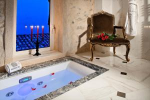 艾日艾泽城堡酒店的浴缸位于带椅子和蜡烛的房间