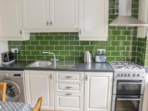 巴利霍尼斯Glor Cottage的厨房配有白色橱柜和绿色瓷砖