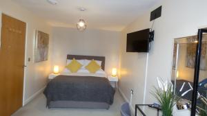 特尔福德Three Storey Townhouse with Parking的一间卧室配有一张带黄色枕头的床和电视。