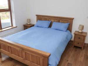 阿基尔Kevin's House的一间卧室配有一张带蓝色床单的床和两张桌子