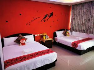 鹅銮鼻垦丁南点民宿的一间卧室设有两张床和红色的墙壁