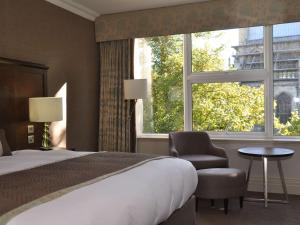 温彻斯特温彻斯特韦塞克斯美居酒店的卧室配有床、椅子和窗户。