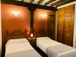 AbanillasLa Posada de Abanillas的一间卧室配有两张床,墙上有两盏灯
