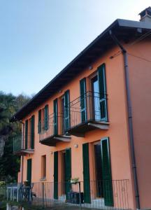莱泽诺B&B Val Valerna的一座橙色的建筑,设有绿色百叶窗和阳台
