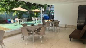 巴拿马城Hostal Familiar Carmencita的一间带桌椅的餐厅和一个游泳池