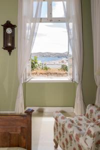埃尔莫波利斯Villa Maria-Syros的客房设有带沙发和时钟的窗户。
