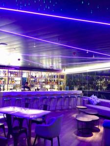 伊洛伊洛J7 Plaza Hotel的酒吧配有桌椅和紫色照明