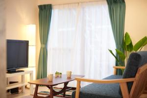 明石市Awaji Portside Holiday Home CHOUTA - Self Check-In Only的客厅配有椅子、电视和桌子