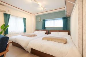 明石市Awaji Portside Holiday Home CHOUTA - Self Check-In Only的卧室内的两张床,配有绿色窗帘