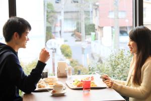 横滨横滨站前里士满酒店(Richmond Hotel Yokohama Ekimae)的坐在餐桌旁吃食物的男人和女人