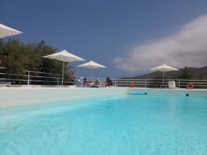 莫拉托斯Milatos Village Cretan Agrotourism Hotel的一个带蓝色水和白色遮阳伞的游泳池