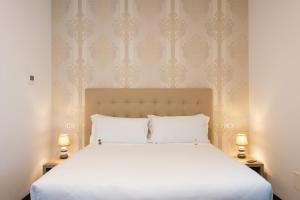 菲乌米奇诺Domus Porto Di Traiano Resort的一间卧室配有一张带两盏灯的大型白色床。