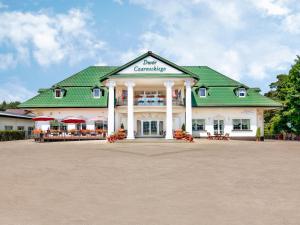 比亚韦斯托克瓦恰米切赫酒店的一座白色的大建筑,设有绿色屋顶