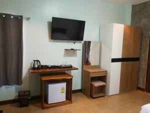 湄宏颂Jeerang Countryside Resort的客房设有书桌和墙上的电视。