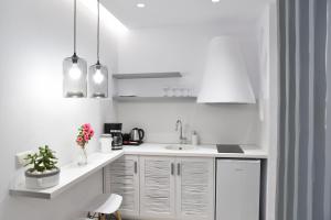 纳克索乔拉Crystal Mare Suites的白色的厨房配有白色橱柜和水槽