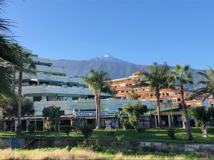 拉克鲁斯巴伊亚普拉亚公寓酒店的一座白色的大建筑,背后有棕榈树和山脉
