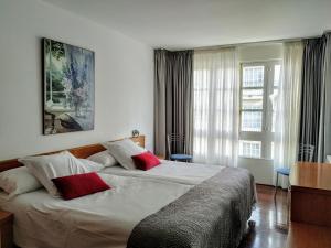 圣地亚哥－德孔波斯特拉Hotel Hórreo by Bossh! Hotels的一间卧室配有一张大床和两个红色枕头