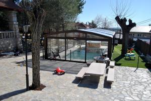 Collado MedianoCasa Rural Mansion Adela con Piscina y Jacuzzi的凉亭,长凳和树