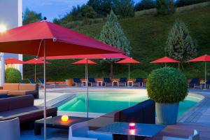 圣艾蒂安高尔夫酒店的一个带红色遮阳伞和桌椅的游泳池