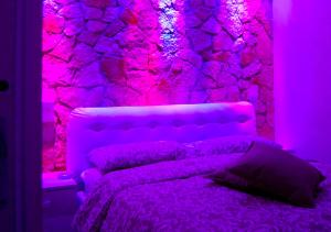 福贾B&b Vittorio Emanuele II的粉红色的卧室,配有一张带岩石墙的床