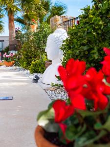 巴伊亚卡萨雷斯Casa Olina的白色雕像坐在红花旁边