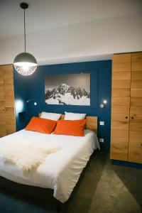夏蒙尼-勃朗峰Appart'Hotel Aiguille Verte & Spa的蓝色卧室配有带橙色枕头的大床