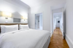 日内瓦瑞士豪华公寓酒店的一间白色卧室,配有一张大床和一个走廊