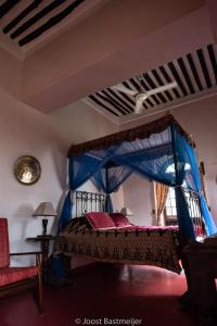 桑给巴尔桑给巴尔皇宫酒店的一间卧室配有一张蓝色天蓬床