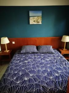 卡尔康LES GRANDS PINS的一间卧室配有一张带蓝色和白色棉被的床