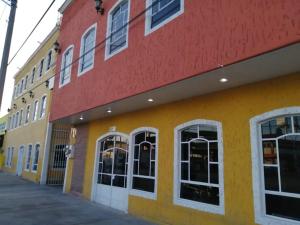 圣路易斯波托西圣路易斯酒店的黄色和红色的建筑,设有白色的窗户