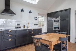 UplymeKilnside的厨房配有黑色橱柜和木桌